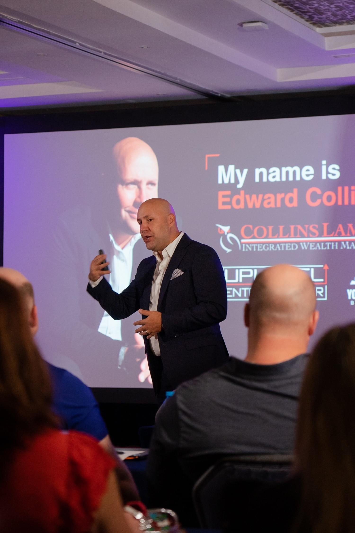 Edward Collins speaking with attendees at a business conference.